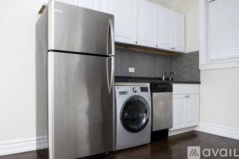 A stainless steel refrigerator and washing machine in a kitchen.