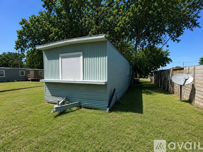 A small metal building with a white door is situated in a grassy area.