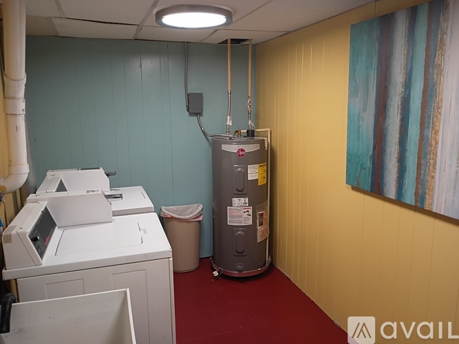 A room with a white printer, a trash can, and a water heater.