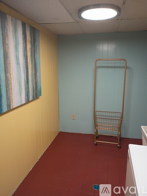 A room with a red floor and a yellow wall with a shopping cart in it.