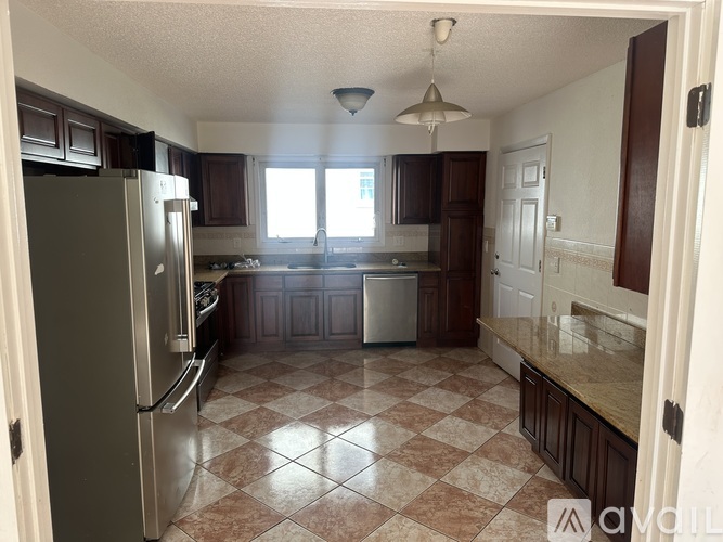 A kitchen with a checkered floor and a refrigerator.