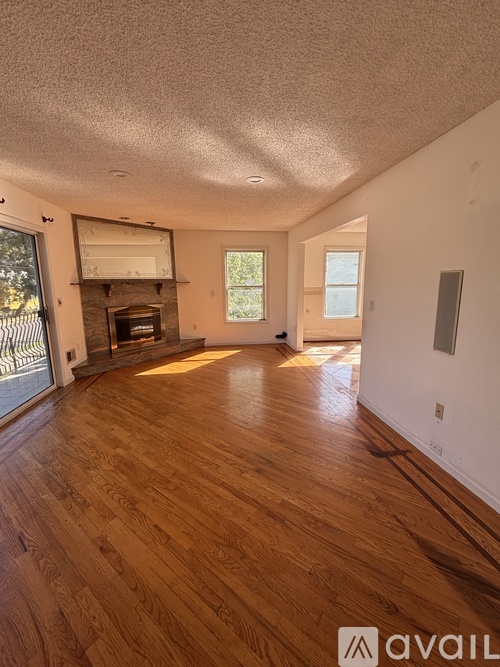 A living room with wood flooring and a fireplace.