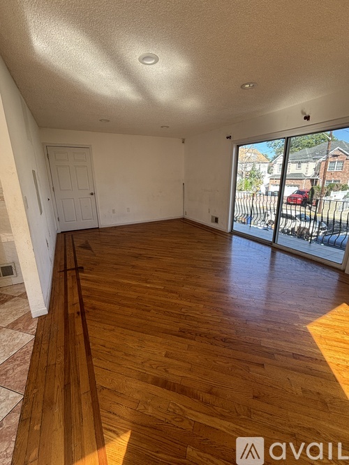 A room with wooden flooring and a sliding glass door.