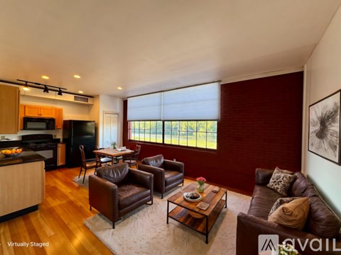 A living room with brown leather furniture and a kitchen area in the background.