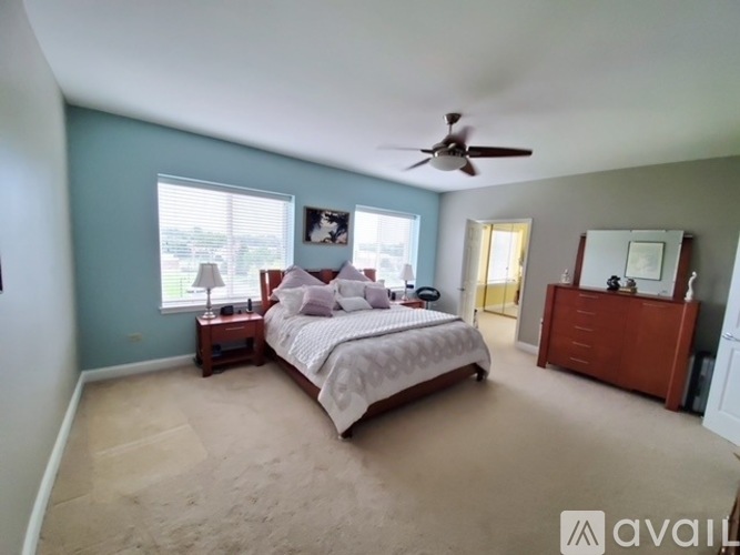 A bedroom with a large bed and a ceiling fan.