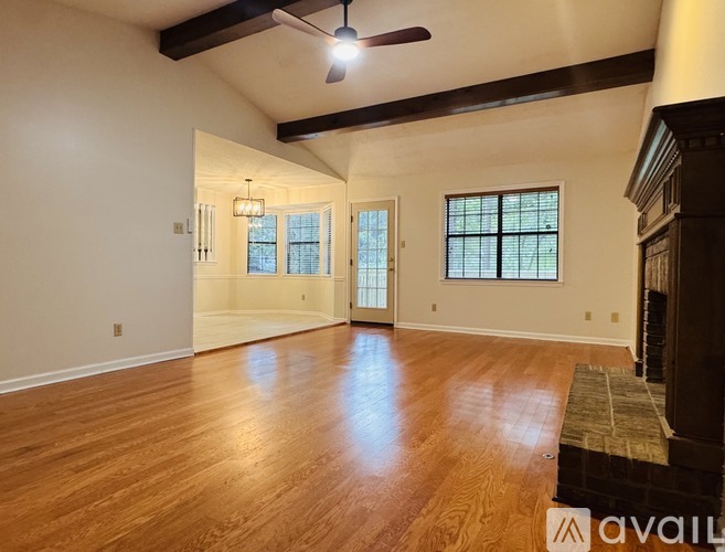A spacious room with wooden floors and a ceiling fan.