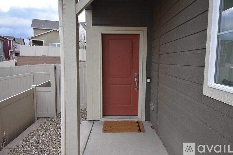 A red door is on the right side of a white fence.