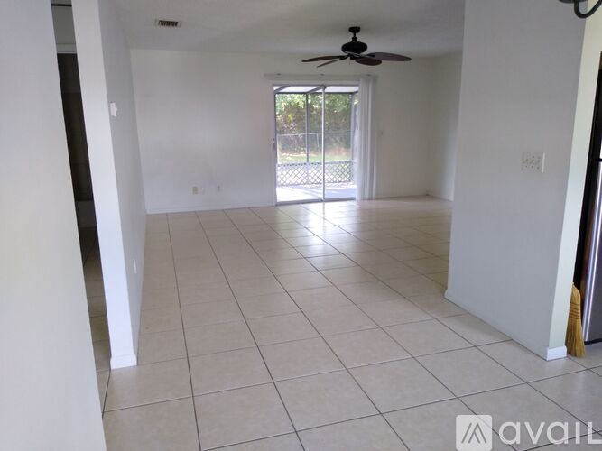 A spacious room with a ceiling fan and sliding glass doors leading to a balcony.
