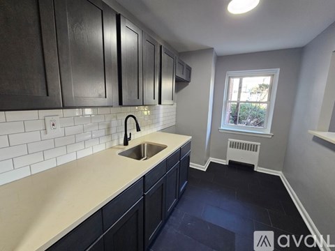 A kitchen with black cabinets and a white sink.