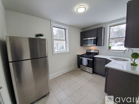 A kitchen with a stainless steel refrigerator and a black microwave.
