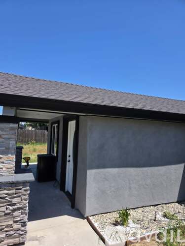 A house with a stone pillar and a grey wall.