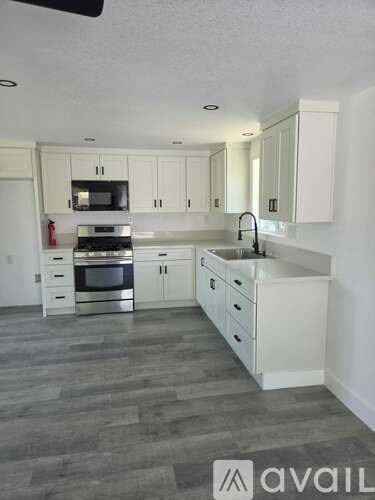 A kitchen with white cabinets and a grey floor.