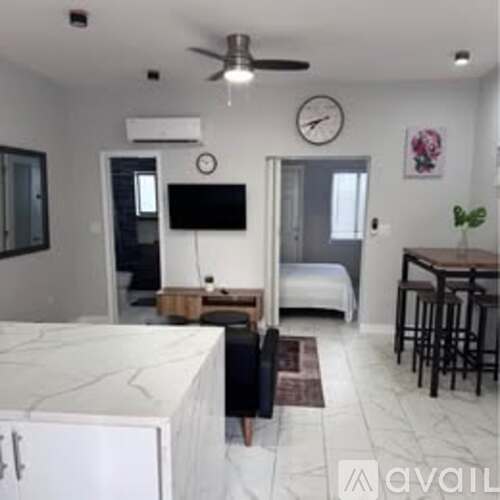 A living room with a white marble counter and a bed in the background.