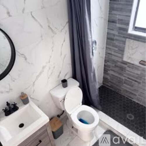 A white toilet with a blue toilet paper roll sits next to a sink in a bathroom.