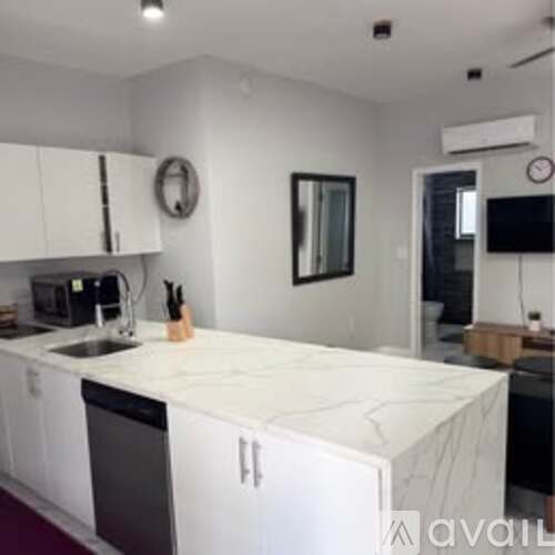 A kitchen with white cabinets and a marble countertop.
