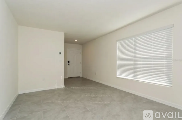 A spacious room with a door and a window with blinds.