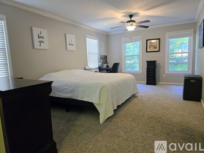 A bedroom with a bed, dresser, and a ceiling fan.