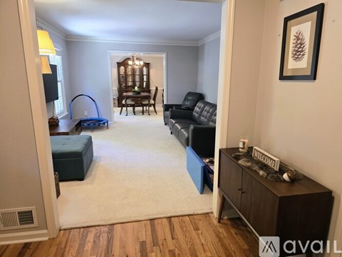A living room with a black leather couch and a wooden cabinet.