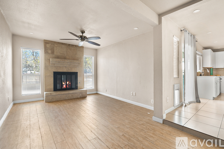 A spacious living room with a fireplace and a ceiling fan.