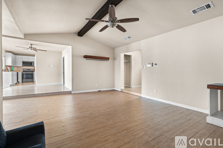 A spacious room with a ceiling fan and hardwood flooring.