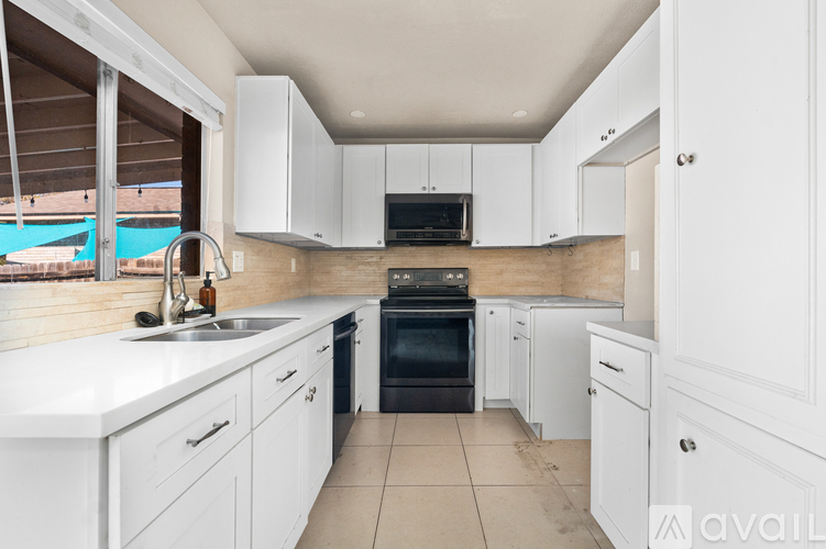 A kitchen with white cabinets and a black oven.