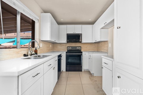 A kitchen with white cabinets and a black oven.