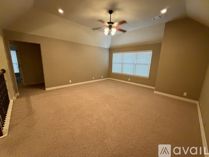 A spacious room with a ceiling fan and carpeted floor.
