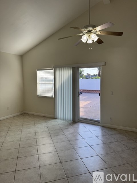 A room with a ceiling fan and sliding glass doors.