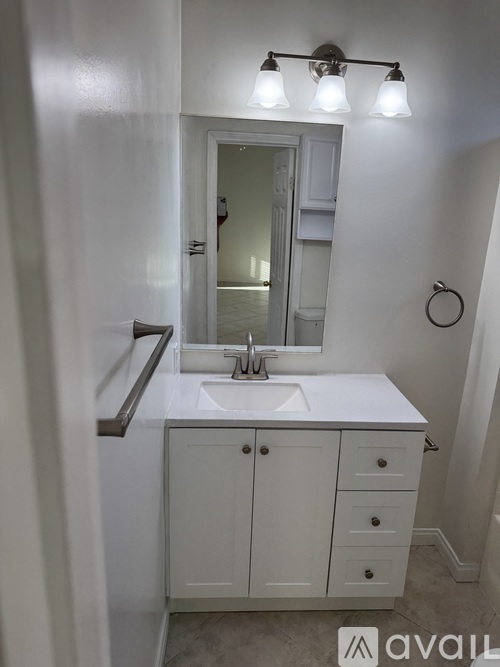 A bathroom with a sink, mirror, and cabinet.