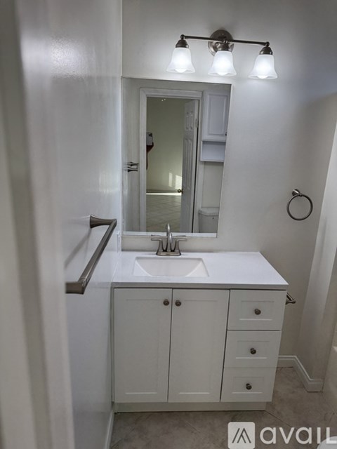 A bathroom with a sink, mirror, and cabinet.
