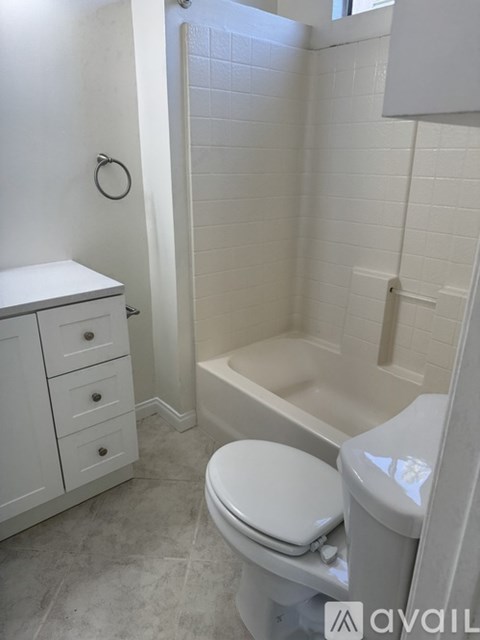 A white toilet in a bathroom with a white cabinet and a white tub.