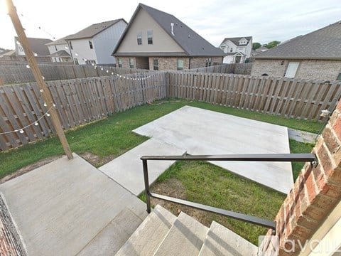 A backyard with a concrete patio and a wooden fence.