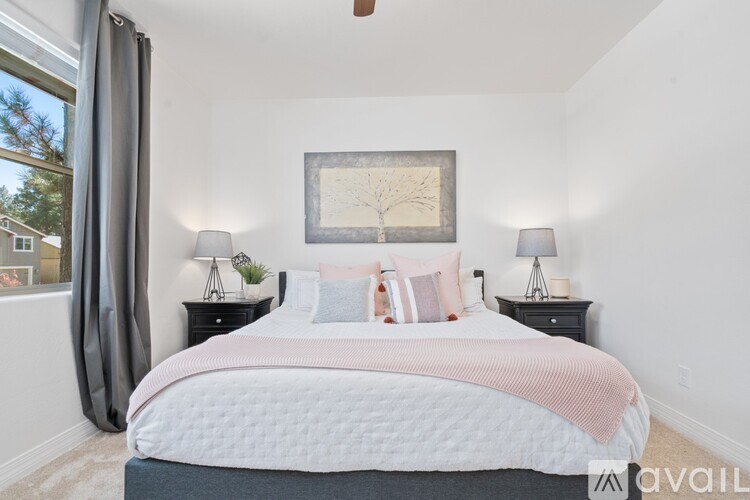 A bedroom with a large bed and two lamps on either side.