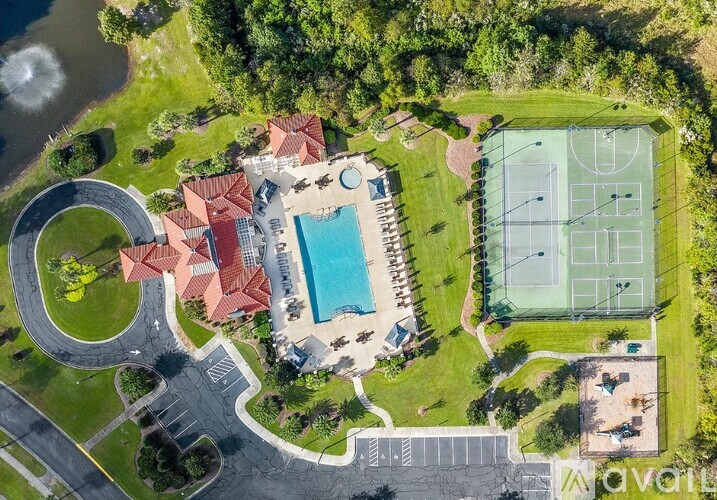An aerial view of a resort with a tennis court, swimming pool, and a building with red roofs.