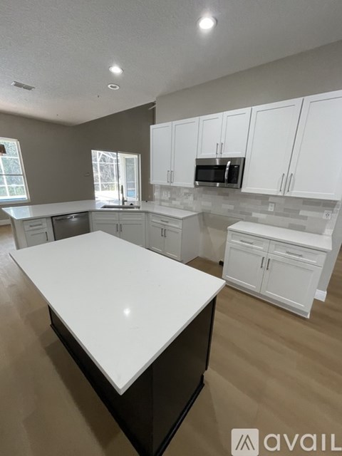A kitchen with white cabinets and a large island.