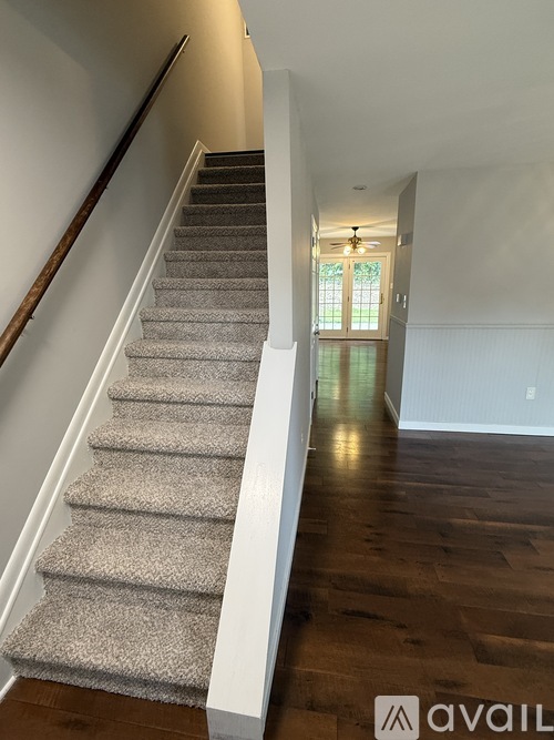 A staircase with a carpeted runner and wooden handrail.