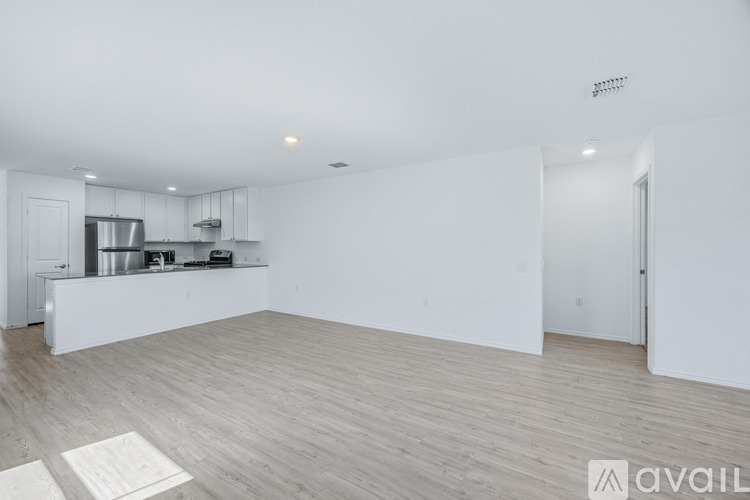 A spacious kitchen with white cabinets and a wooden floor.