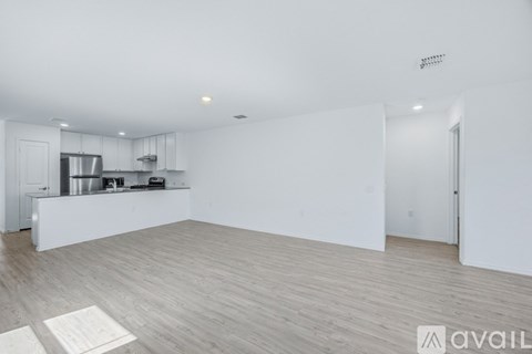 A spacious kitchen with white cabinets and a wooden floor.
