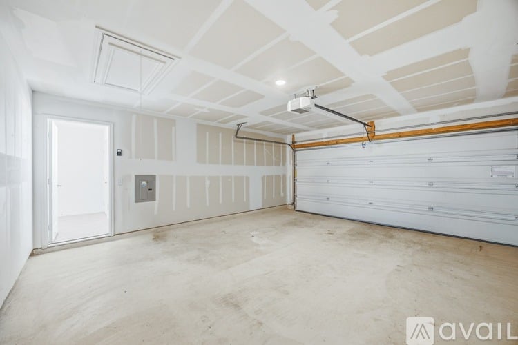 A spacious garage with a white door and a white ceiling with wooden beams.