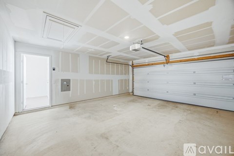 A spacious garage with a white door and a white ceiling with wooden beams.