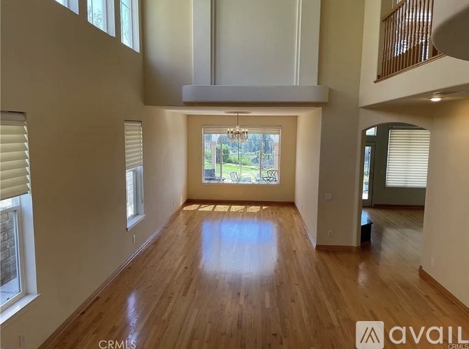 A spacious room with wooden floors and a large window overlooking a green landscape.