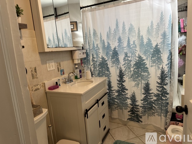 A bathroom with a shower curtain that has a forest scene on it.