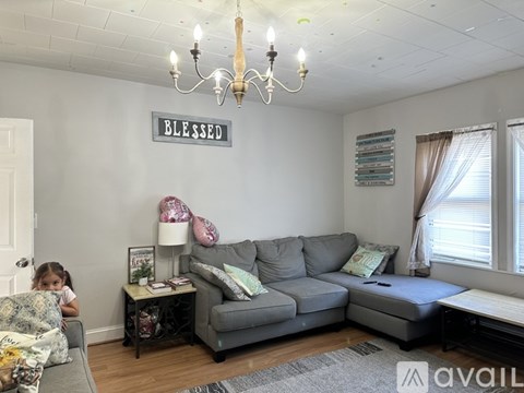 A living room with a grey couch and a chandelier.