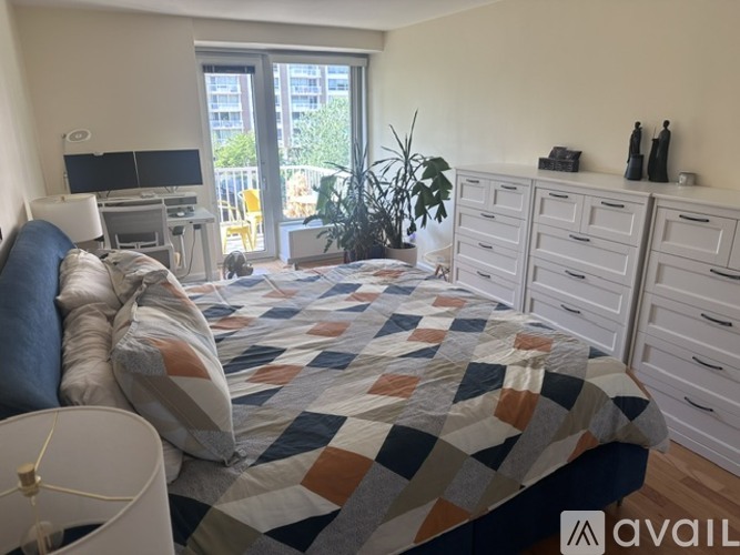 A bedroom with a bed, a desk, and a window.