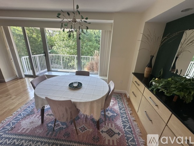 A dining room with a round table and chairs, a rug, and a chandelier.