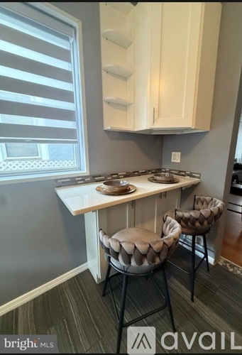 A kitchen with a table and two chairs.