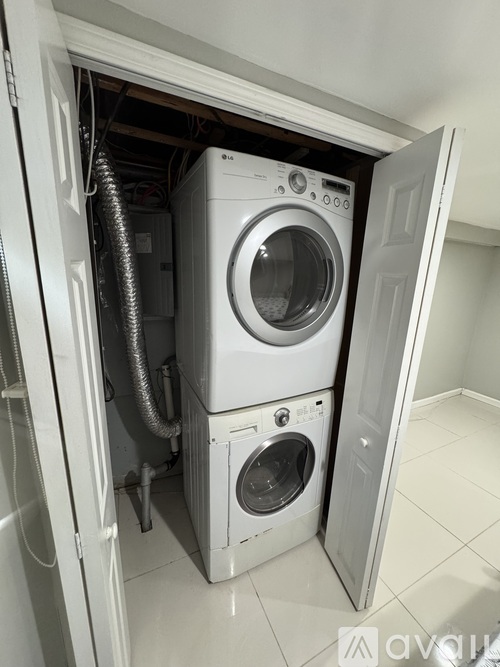 A washing machine is installed in a small space under a door.