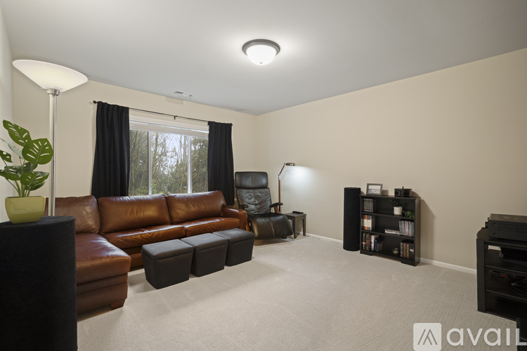 A living room with a brown leather couch and a white floor lamp.