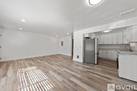 A kitchen with white cabinets and a refrigerator is visible through a window.