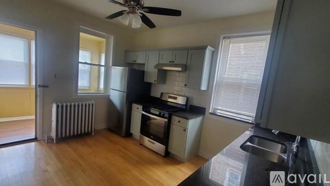 A kitchen with a black counter top and a fan on the ceiling.